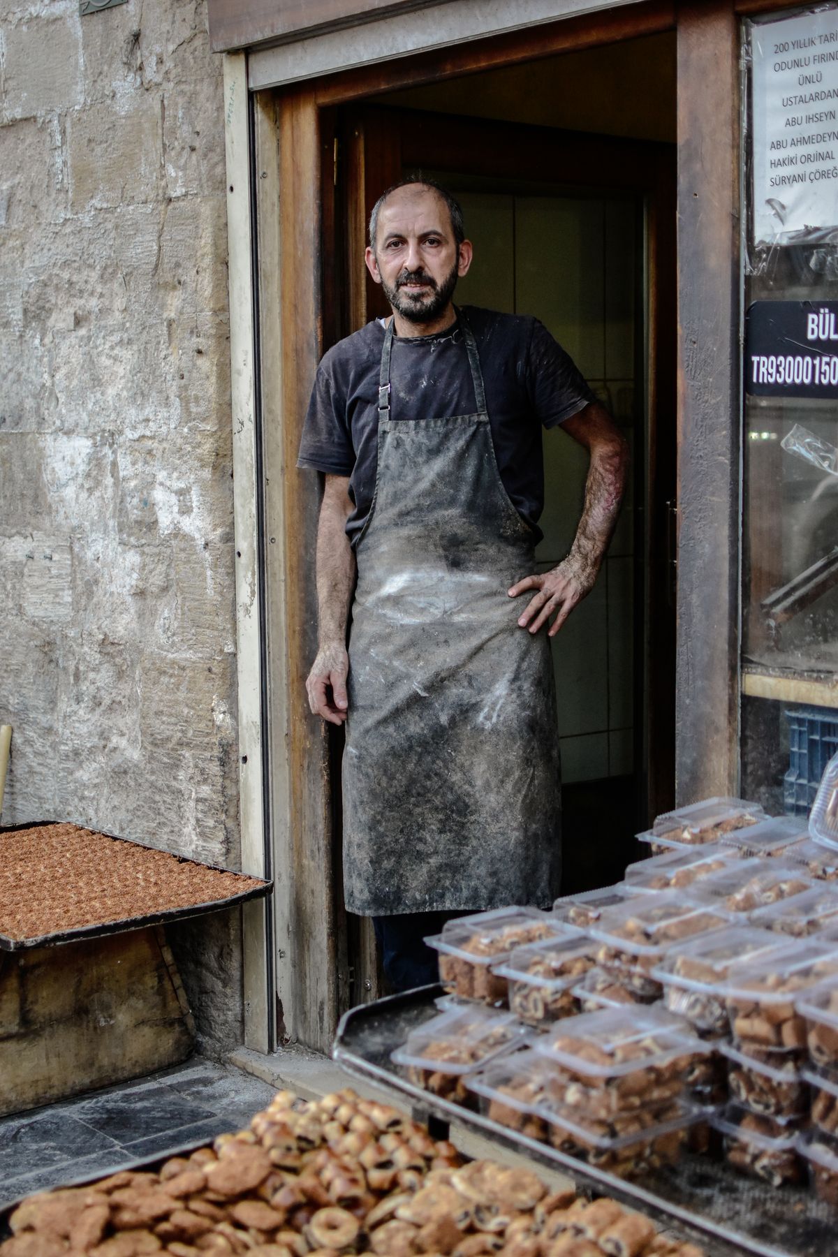 A baker standing in the doorway of his bakery with fresh bread